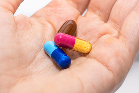 Close-up colorful powder soft capsules pill in hand. blue pink yellow brown medicine supplement...