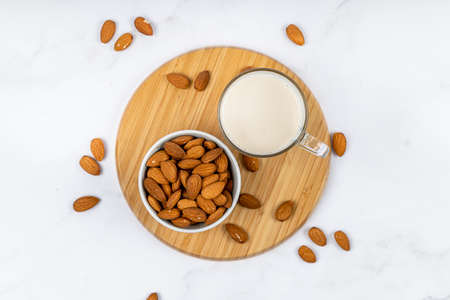 Almond milk in a glass with almond on a wooden tableの写真素材