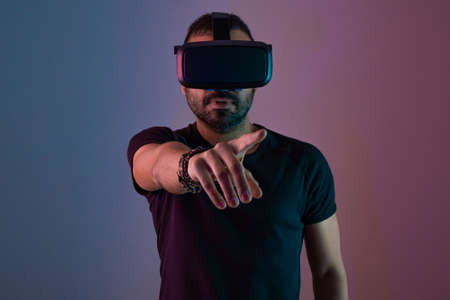 Young man in VR glasses headset interact with virtual reality in color neon light, future technology, education video gamingの写真素材