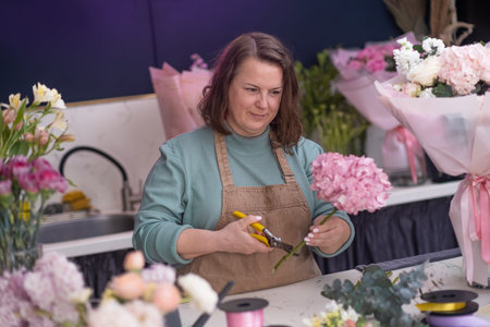 inside the charming flower shop, the creative female business owner expertly arranges a stunning...