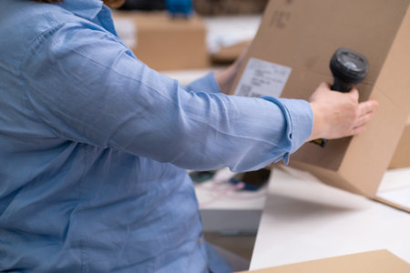 logistics shipping online orders concept. close up of warehouse worker scanning barcode on package box for tracking delivery, e-commerce. SME.の写真素材