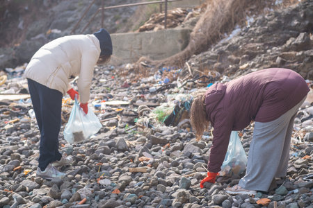 A group of volunteers is cleaning up a polluted beach by collecting plastic garbage, in an effort to preserve the environment and protect marine lifeの写真素材