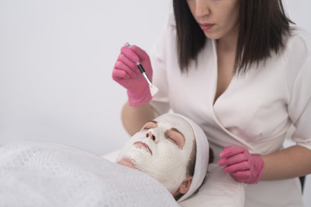 aesthetic beauty doctor applying face masks with brush and perform full facial treatments for middle age womanの写真素材