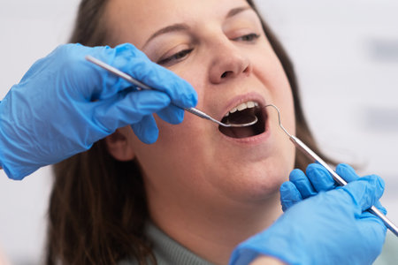 female patient undergoing dental care with a professional dentist using dental mirror and equipment in a state-of-the-art dental office.の写真素材