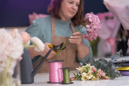 ordering flowers online, the experienced florist in the flower shop works to make a colorful bouquet, ready for delivery by the trusted courier service.の写真素材