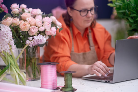 skilled professional florist in her prime, fashioning lovely bouquets while donning her apron at the...