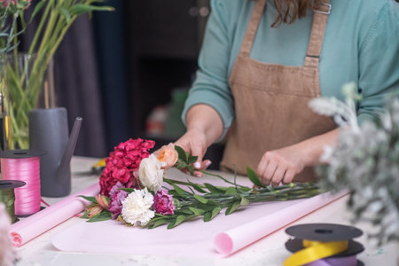 Expert flower decorator using her hands to create a beautiful bouquet of pink roses up close. slower shopの写真素材
