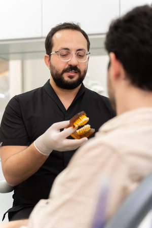 Doctor in black uniform recommending patient to install dental braces and solve orthodontic problems...