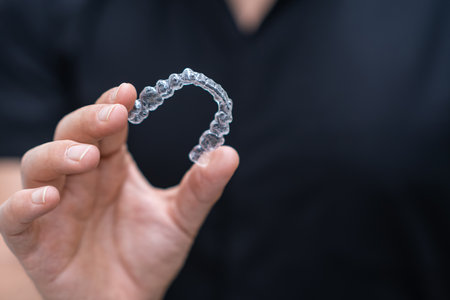 Professional dentist presenting clear aligners orthodontic treatment tool for problematic teeth in contemporary stomatology center doctor holding device closeupの写真素材