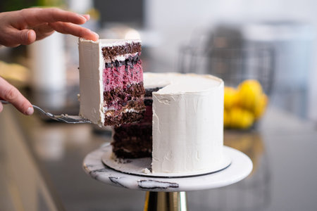 Woman taking cut piece of delicious sugar free cake covered with white mastic with spatula on...
