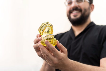 Positive doctor showing artificial human jaws with contemporary dental braces used for professional...