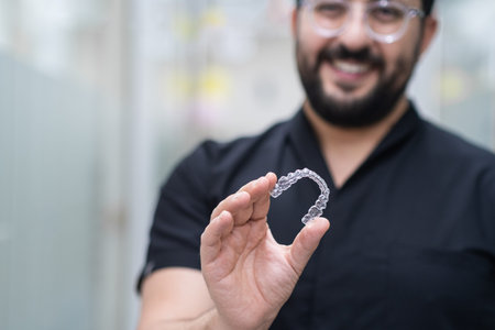 Positive dentist demonstrating clear aligners used for effective teeth straightening in contemporary...