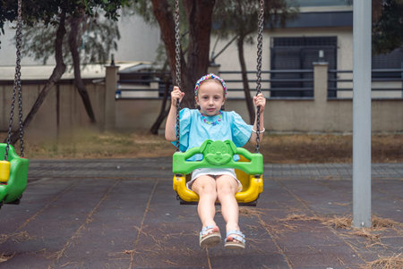 Happy girl laughs while swinging in the city park playground.