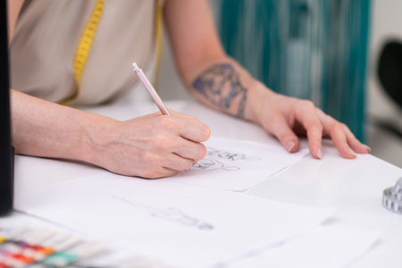 Woman draws dress model sitting at desk in clothes atelier talented designer makes sketch of stylish apparel for women in fashion studio closeup sewing industryの写真素材