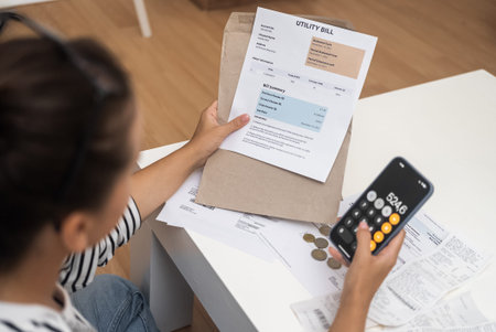 Home Accounting: Female hands handle bills from an envelope, calculating on a mobile phone at home.
