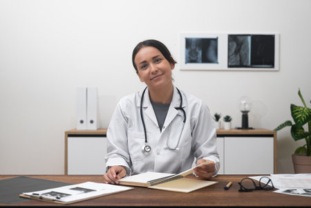Warm Virtual Welcome: With a smile, a female doctor looks at the camera, extending a friendly welcome to patients during an online appointment.の写真素材