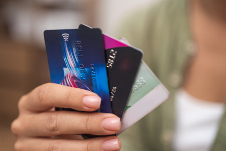 Woman hand with gentle manicure holds several colored credit cards for making online payments in store concept of technology and shopping devices on blurred backgroundの写真素材
