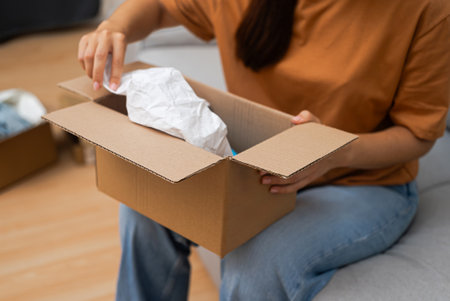 Effortless Shopping: With excitement, she unwraps her package, enjoying her online purchase and the convenience of shipping and delivery.の写真素材