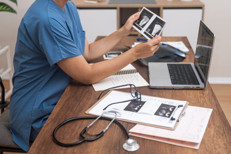 Young female doctor looks at pictures of ultrasound examination of patient medical specialist takes...
