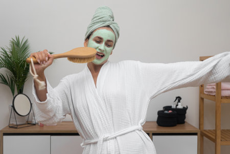 Home Spa Party: In her bathrobe, she sports a clay mask, using a hairbrush as a mic, dancing with a towel on her head, having a fabulous time.の写真素材
