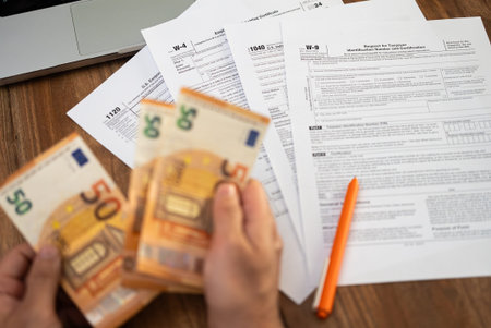 Man freelancer counts euro banknotes preparing for filling various tax forms to report annual income...