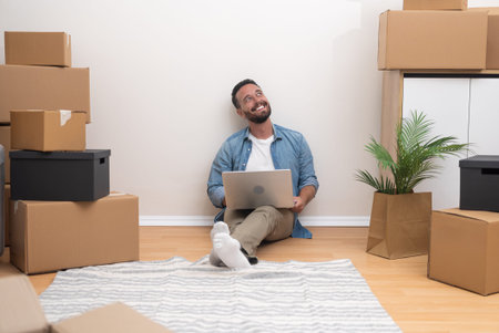 Young man in classic clothes sits on floor with carpet emitting positive emotions with happy...
