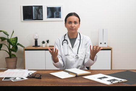 E-Care Introduction: female doctor looks at the camera, talking gesturing to patients during online consultation appointments.の写真素材