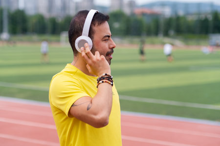 dynamic city sports stadium, portrait of young man trains and finds inspiration in his favorite music in headphones, enjoying the uplifting exercise with music.の写真素材