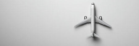Minimalist composition featuring a white airplane model resting on a white backdrop, offering ample copy space for travel related messagingの素材