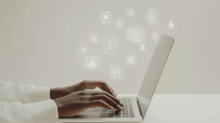 Social media manager is using laptop with various app icons floating above the keyboard, representing social media marketing and online communicationの素材