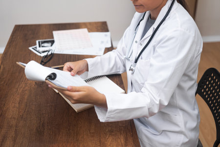 Therapists Analysis: Seated in a modern clinic, a young female therapist doctor provides a professional analysis of patient test results.の写真素材