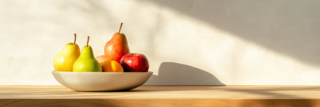Modern kitchen scene featuring a bowl of ripe pears, apples, and an orange bathed in sunlight on a wooden tabletop, creating a warm and inviting atmosphereの素材