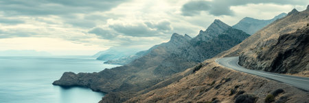 Scenic coastal road winding through rugged mountains along the mediterranean sea, offering breathtaking views and showcasing the beauty of nature under cloudy skiesの素材