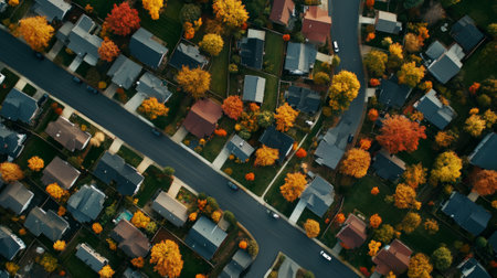 Aerial view captures the beauty of a suburban neighborhood in autumn, showcasing colorful trees, houses with varying roof colors, and cars driving on the streetsの素材