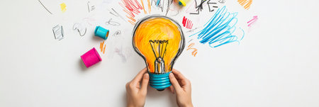 Two hands holding a drawing of a light bulb surrounded by colorful marker scribbles on a white surface, representing the concept of creativity and new ideas in a design or business contextの素材