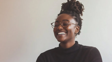 Portrait of a cheerful young african american businesswoman wearing glasses, laughing and feeling happy, expressing positivity and success in businessの素材