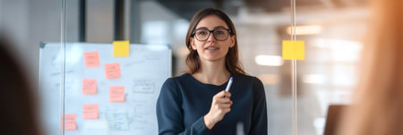 Businesswoman leads a meeting, presenting a strategy on a whiteboard covered with sticky notes, engaging with her team in a modern office environmentの素材