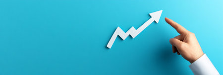 Businessman pointing upward trending arrow, representing business growth, stock market increase, or financial success on a vibrant blue backgroundの素材