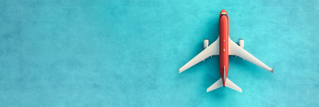 Minimalist travel concept featuring a red and white toy airplane soaring against a vibrant turquoise backdrop, symbolizing adventure, wanderlust, and the excitement of exploring new destinationsの素材