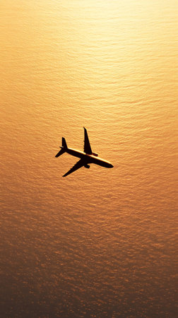 Passenger airplane flying over a golden ocean during a beautiful sunset, symbolizing business travel, international connections, and global commerceの素材