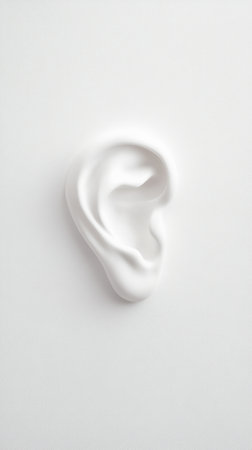 White anatomical model of a human ear resting on a white background, illustrating concepts of hearing healthcare, audiology, and the complexities of hearing lossの素材