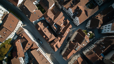 Aerial view captures the geometric patterns formed by the red tiled roofs of buildings in a quaint european town, showcasing the architectural layout and urban designの素材