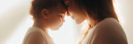 Mother and baby are touching foreheads, enjoying a quiet moment of connection and love, bathed in warm, soft light, creating a serene and heartwarming atmosphereの素材