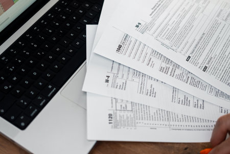 Business company accountant prepares for filling different tax forms indicating annual income ensuring paying enough taxes throughout year at workplace with modern laptopの写真素材