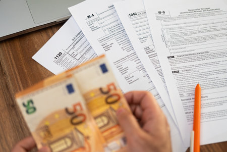Responsible taxpayer counts euro banknotes calculating income sources providing transparent and accurate financial information for filling tax forms at wooden deskの写真素材