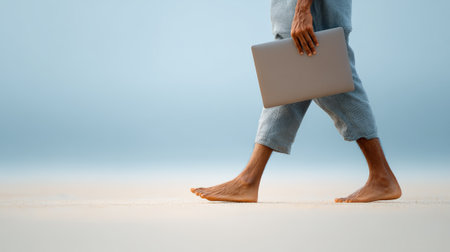 Freelancer walking barefoot on the beach carrying a laptop, enjoying work and travel lifestyle, combining work with vacation in a beautiful tropical destinationの素材
