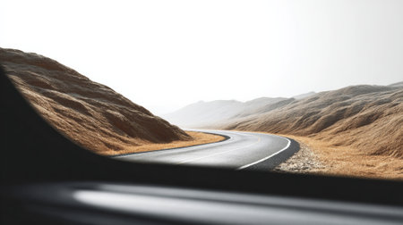 The sun shines brightly on a winding asphalt road cutting through a desert landscape, viewed from inside a vehicle, promising adventure during a summer road tripの素材