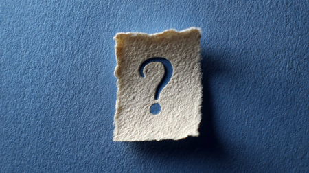Textured white paper with a question mark cutout, resting on a blue background, symbolizing concepts of doubt, uncertainty, problem solving, and seeking informationの素材