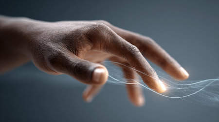 Close up of a hand interacting with glowing, flowing light trails, symbolizing the connection between humans and artificial intelligence, creating a futuristic and technological atmosphereの素材