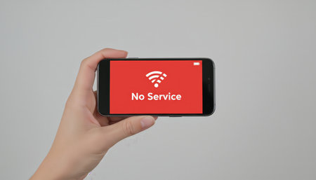 Hand holding a smartphone displaying a red screen with a white wi fi icon and no service text, indicating a connection problem, technical issue, or network outageの素材